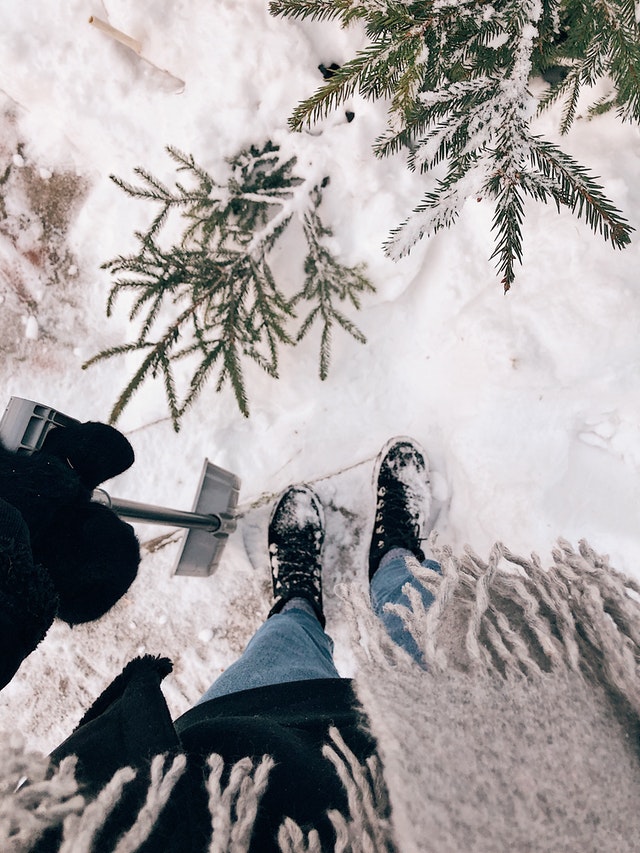 first-person perspective: looking down at feet, snowy ground, snow shovel